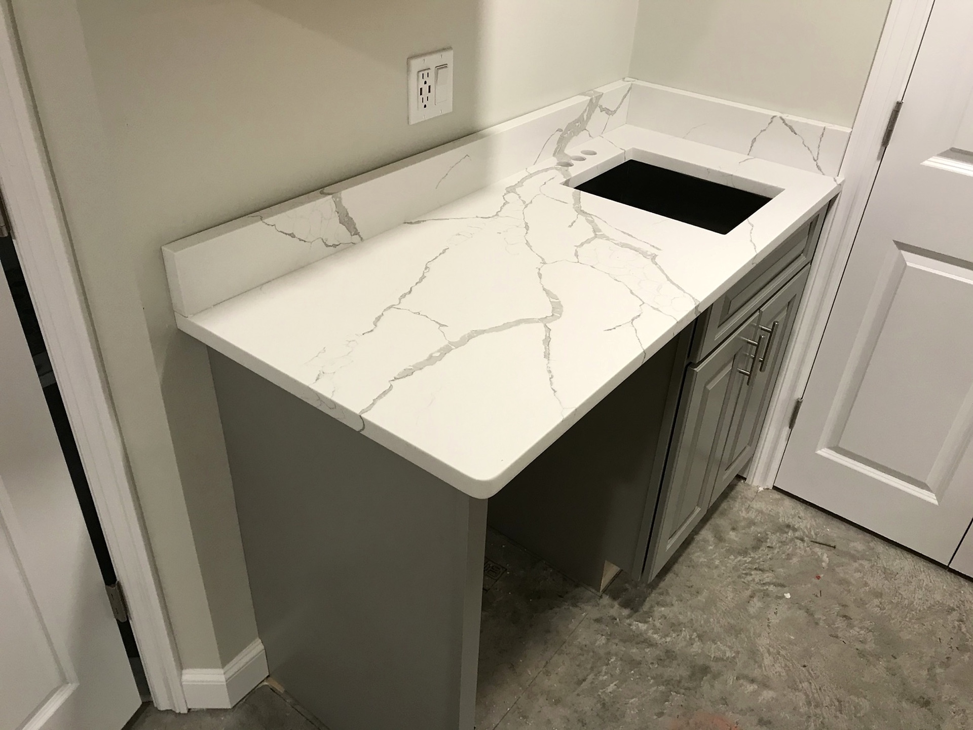 Compact bathroom vanity with a white veined stone countertop and matching backsplash