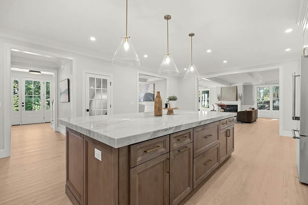 Wood island with a light veined stone countertop in a completed kitchen