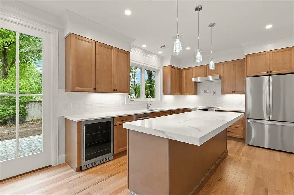 Light oak cabinetry with white veined stone countertops and glass pendants