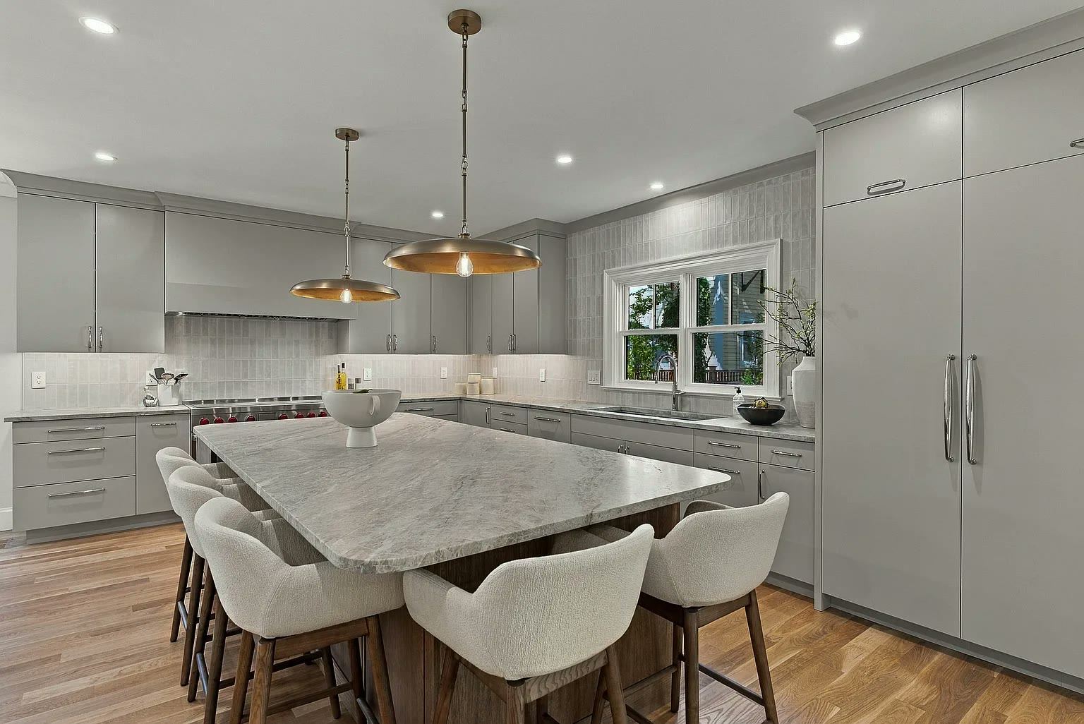 Open-plan kitchen with a large stone island, grey cabinetry and dining seating